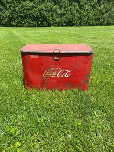 an old coca cola cooler sitting in the grass