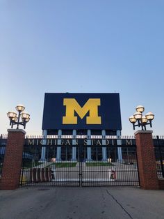 the entrance to michigan state university in front of a gate with street lamps on it