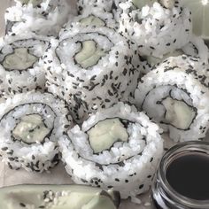 several sushi rolls with black sesame seeds on them next to a jar of sauce