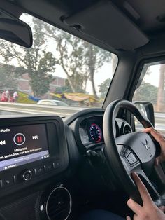 a person driving a car on the road with their hands on the steering wheel and an electronic screen