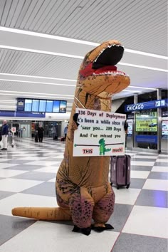 a large inflatable dinosaur with a sign attached to it's back at an airport