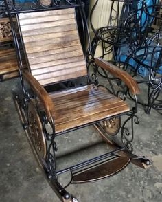 a wooden and metal rocking chair sitting on top of a floor next to other chairs