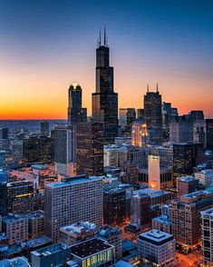 an aerial view of the chicago skyline at sunset, with skyscrapers in the foreground