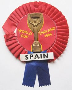 a red rosette with the words world cup placed on it and blue ribbon around it