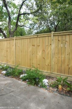 a wooden fence in the middle of a yard with flowers and plants growing around it