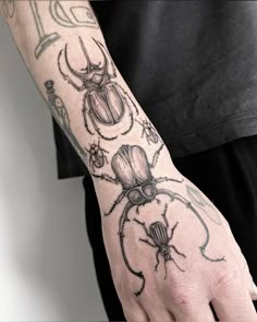 a person with a tattoo on their arm holding onto a hand that has two bugs on it