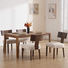 a dining table with four chairs and a vase on the table in front of it