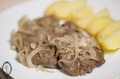 a white plate topped with meat covered in gravy and sliced pineapples