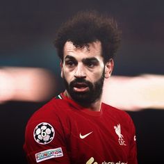 a close up of a soccer player wearing a red shirt and black hair with an afro