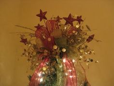 a christmas tree decorated with red and white ribbons, lights and ornaments in a vase