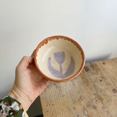 a hand holding a bowl with flowers painted on it