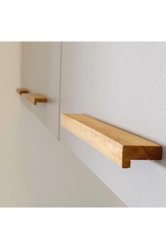 two wooden shelves on the side of a white wall