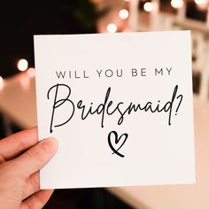 someone holding up a card that says, will you be my bridesmaid?