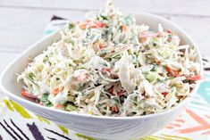 a white bowl filled with coleslaw salad on top of a colorful table cloth