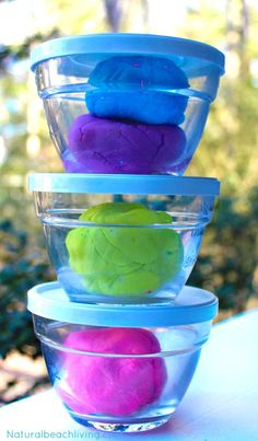 three plastic bowls filled with different colored playdoughs sitting on top of a table