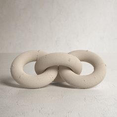 two white knitted rings sitting on top of each other in front of a wall