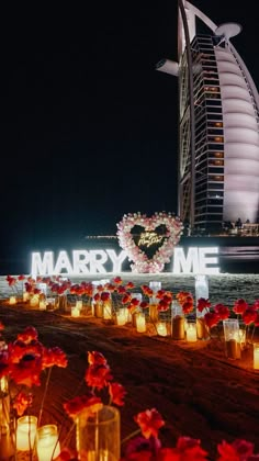 many candles are lit up in front of the burj hotel and sign that says marry me