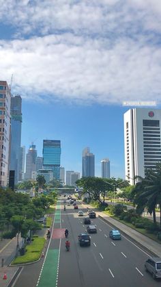 cars are driving down the road in front of tall buildings and palm trees on either side