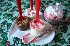 some candy and marshmallows are on a white plate with red spoons