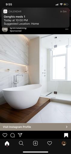 a large white bathtub sitting in the middle of a bathroom next to a window