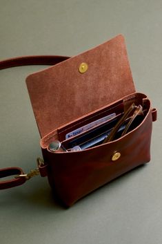 A daily companion that truly holds just the essentials. Keys, phone, chapstick, and sunglasses fit snug yet comfortably in this itty bitty bag that can be worn cross body, fanny, or sling style. Removable adjustable strap. Front magnet closure. Interior two slot card pocket. Handmade in Austin, TX using full grain, vegetable tanned leather and durable brass hardware. Made in USA 100% Vegetable Tanned Leather Measures 7.25" wide x 1.5" deep x 4.5" tall Interior Pocket 4.25" x 2.25" Leather Cross Bag, Leather Crossbody Bag For Women, Cross Body Leather Bag, Diy Leather Crossbody Bag, Leather Ideas Handmade, Leather Products Ideas, Leather Purse Strap, Sunglasses Fit, Leather Phone Bag