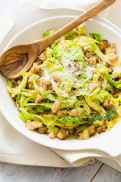 a white bowl filled with broccoli and cheese on top of a wooden spoon