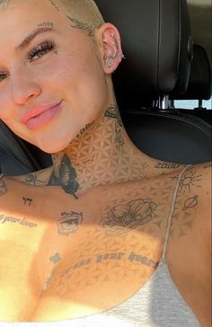 a woman with tattoos on her chest sitting in a car