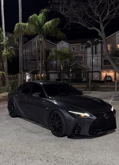 a black sports car is parked in front of some palm trees and houses at night