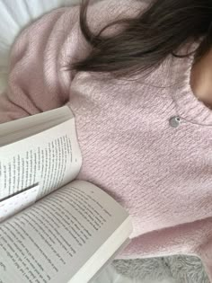 a woman laying in bed reading a book with her head resting on an open book