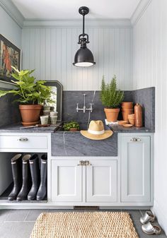 a kitchen with white cabinets and gray counter tops, potted plants on the wall