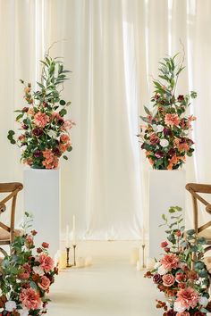 three tall white vases with flowers and greenery