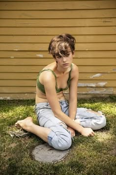 a woman sitting on the ground in front of a house with her eyes closed and hands clasped