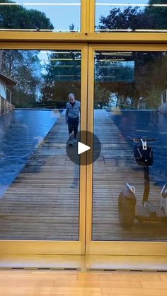 the reflection of two people walking in front of a glass door on a wooden floor