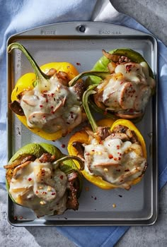 stuffed bell peppers with cheese and meat on a baking sheet next to a blue towel