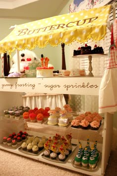 a display case filled with lots of cupcakes and other desserts under a yellow umbrella