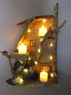 lighted candles are placed on the shelf in front of a house shaped like a tree branch