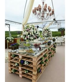 a table with flowers on it under a chandelier in the middle of an outdoor area