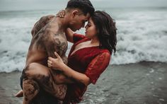 a young man and woman are hugging in the water at the beach with mud all over them