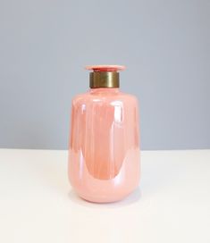 a pink vase sitting on top of a white table