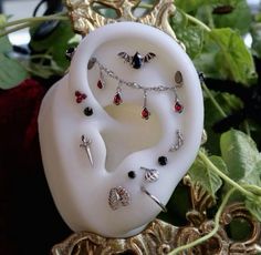 a white brooch with various jewels on it sitting in front of some green leaves