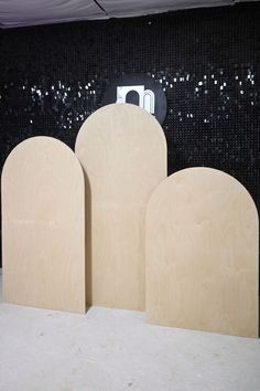 three unfinished wooden blocks sitting in front of a black and white mosaic wall with glittery sequins