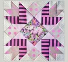 a pink and purple patchwork quilt with an elephant on it's center piece