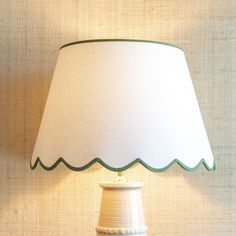 a white lamp with a green trim on the bottom and a beige shade over it