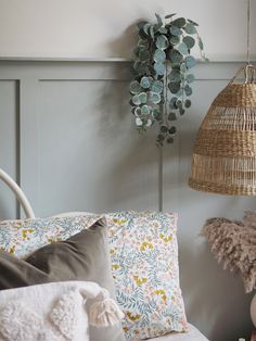 a wicker basket hanging from the ceiling above a bed with pillows and blankets on it