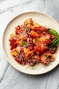 a white plate topped with pasta covered in sauce and parmesan sprinkled cheese