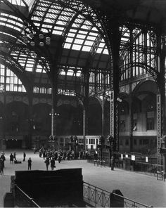 an old black and white photo of people in a train station with large glass windows