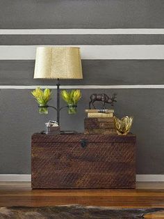 a lamp on top of a wooden box next to a table with two vases