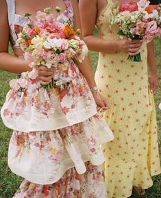 two women in dresses holding bouquets of flowers