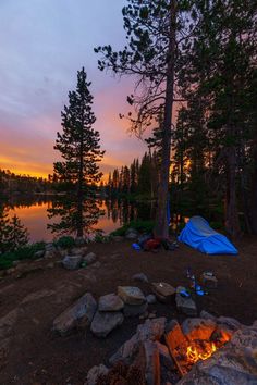 there is a tent set up next to the fire pit at this campsite by the lake