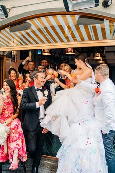 a group of people standing around each other in front of a building holding champagne flutes